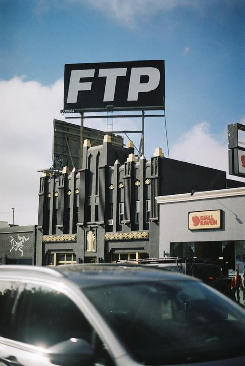 A large billboard with the letters "FTP" is visible above a building with art deco architectural details.