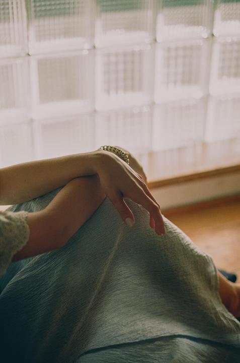 A woman's arm and leg are visible in front of a glass block window.