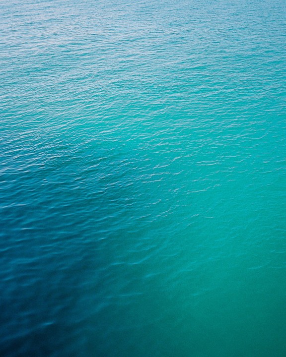 The surface of the ocean shows a gradient of blue and green hues.