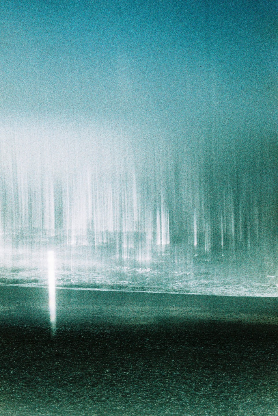 A long exposure captures the light trails of a city at night, with a bright vertical light streak in the foreground.