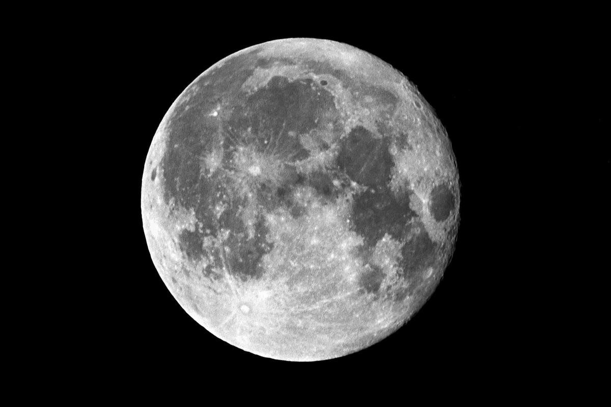 The full moon is visible against a black sky, showing its craters and texture.