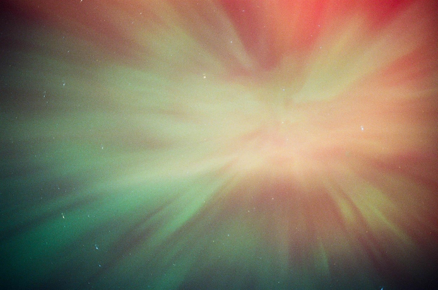 The aurora borealis glows green and red in the night sky, with small stars visible.