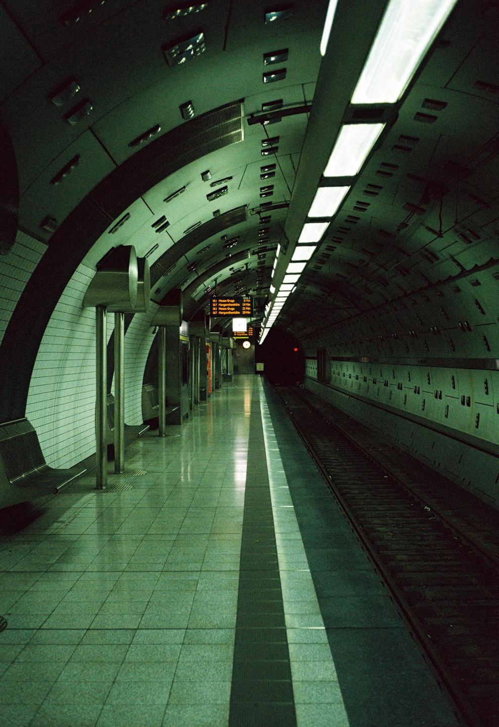 A long, empty subway platform stretches into the distance, illuminated by overhead lights.