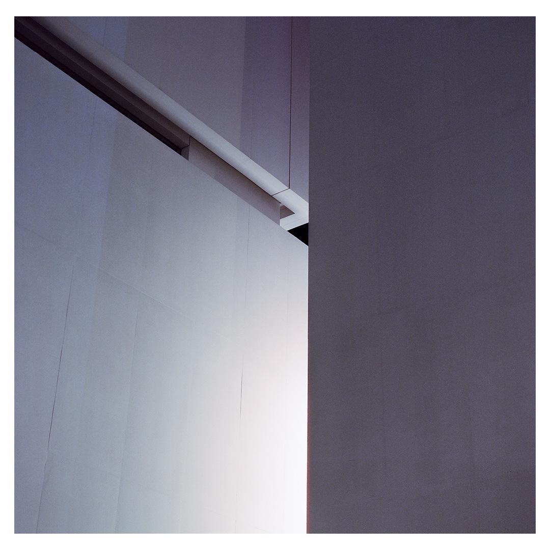 A white wall with a bright light source on the left is contrasted by a dark gray wall on the right.