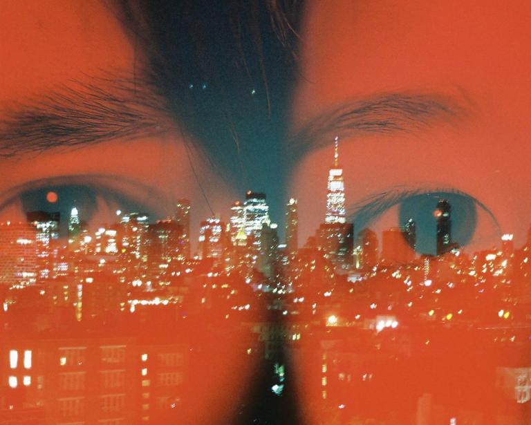 A double exposure shows a cityscape at night overlaid on a pair of eyes.