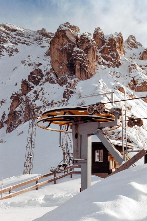 A ski lift with chairs is visible in a snowy mountain landscape with rocky peaks.