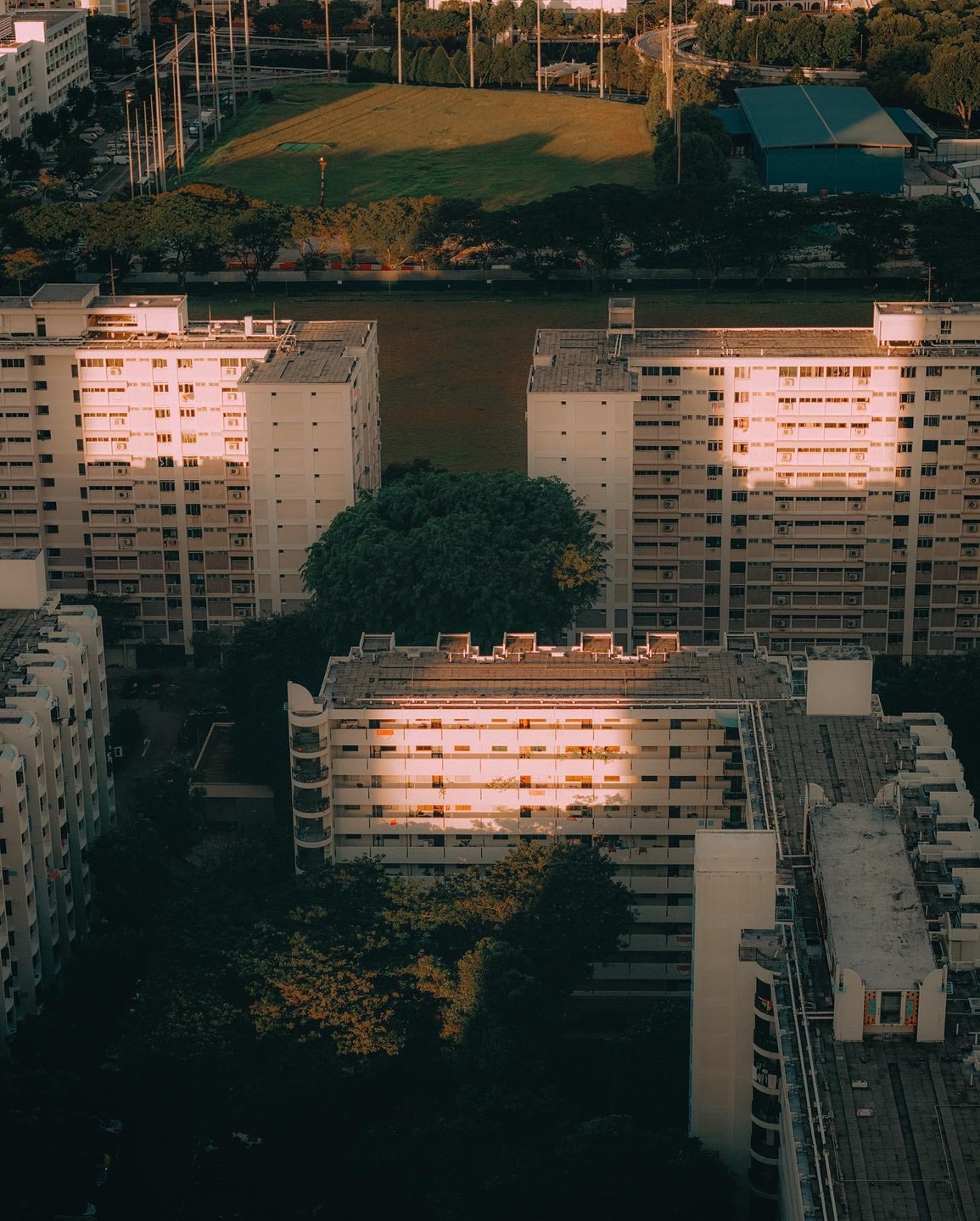 An aerial view shows apartment buildings and a field with a patch of sunlight on one building.