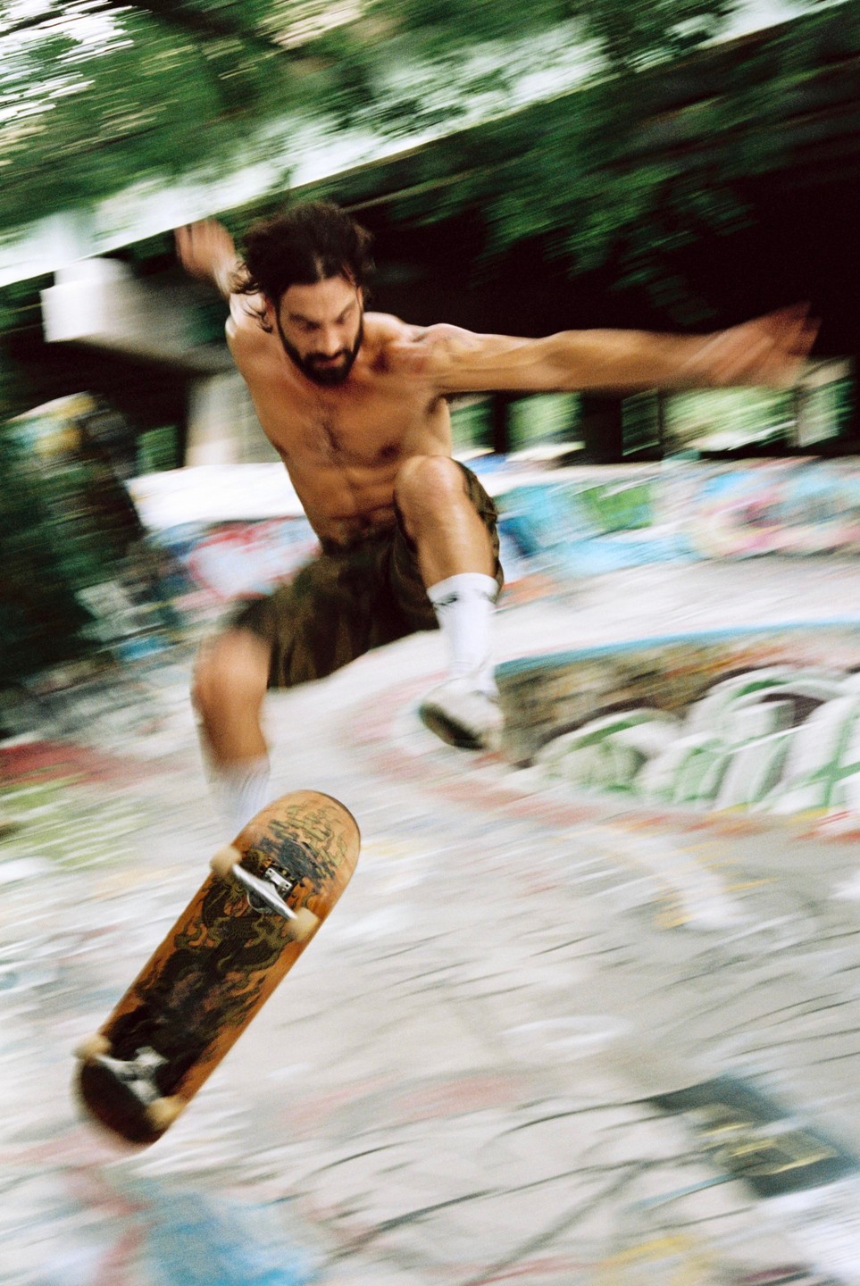 A man jumps with a skateboard in a skatepark.