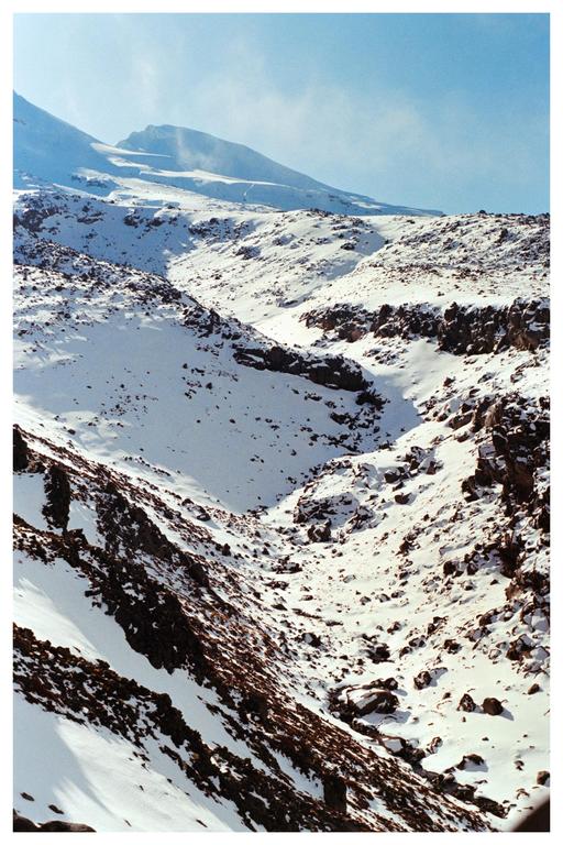 A snowy valley with rocky slopes is visible under a clear blue sky.