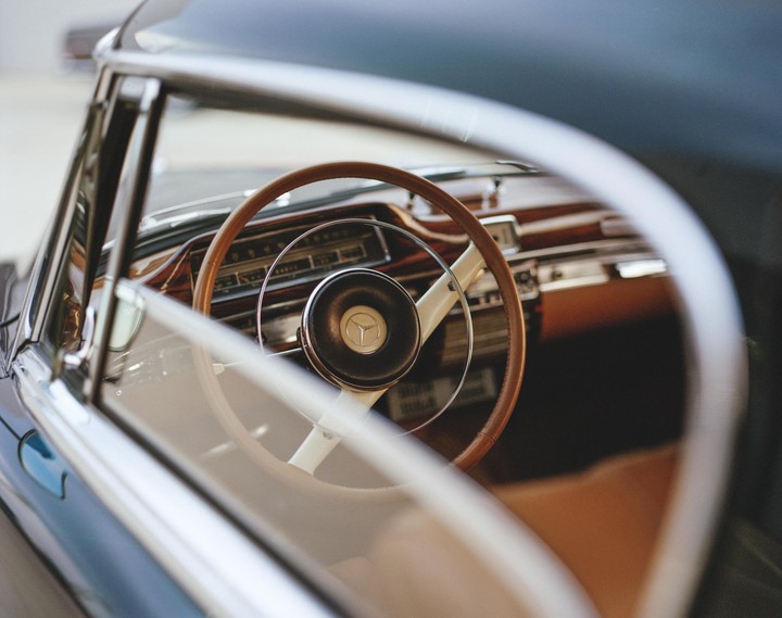 The interior of a vintage Mercedes-Benz car is visible through the open window.