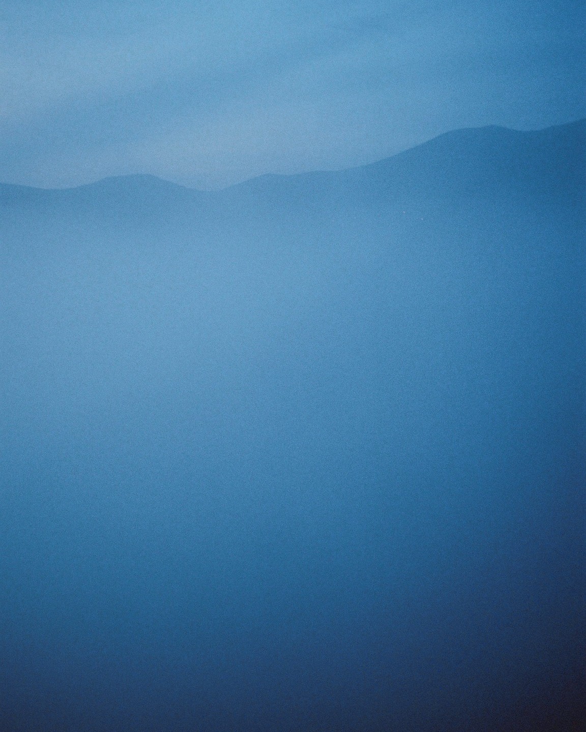 A hazy mountain range is visible through a blue fog.