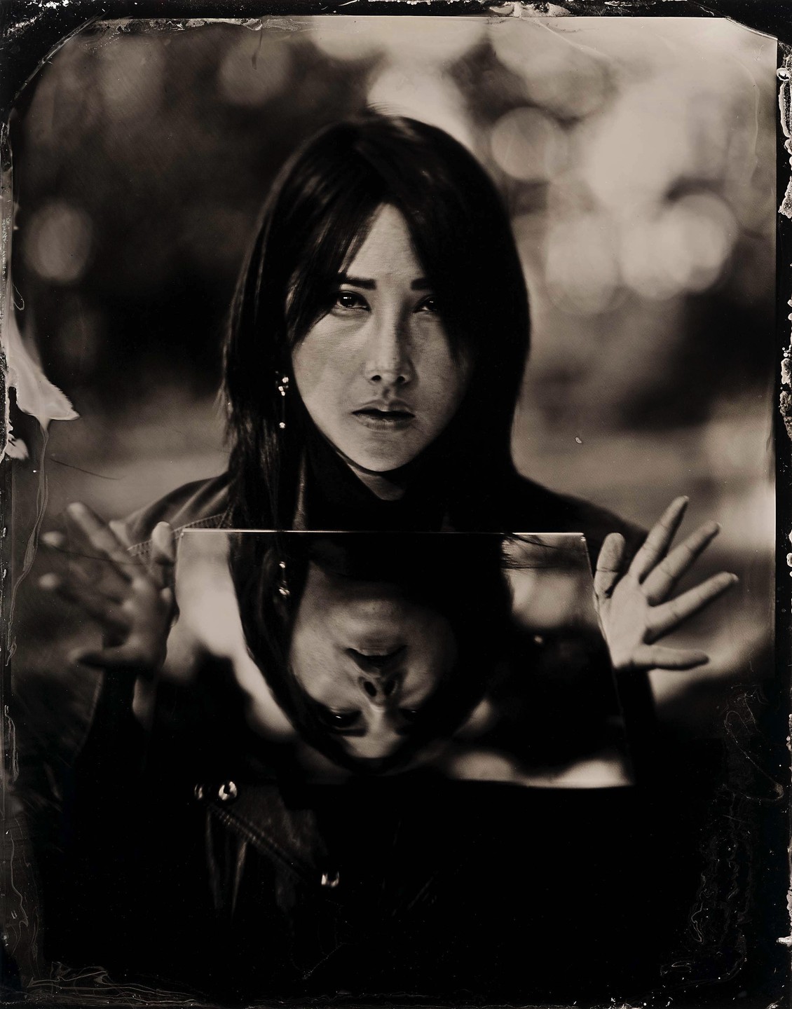 A woman holds a mirror reflecting her face upside down.