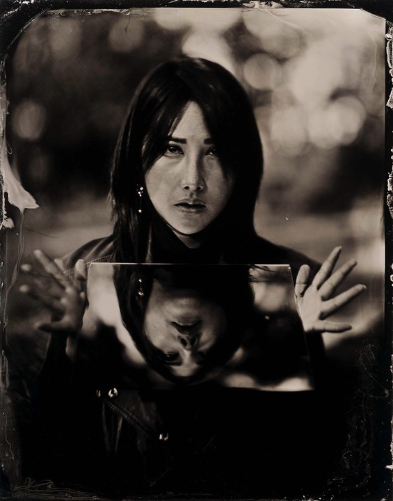 A woman holds a mirror reflecting her face upside down.
