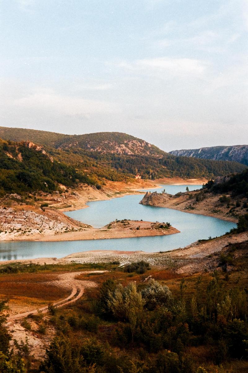 A winding river flows through a valley surrounded by hills and mountains.