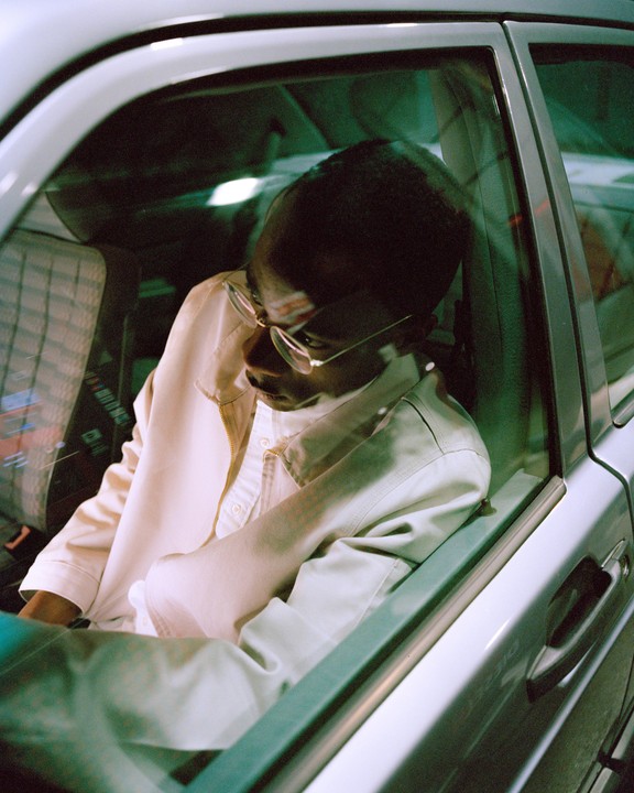 A man wearing glasses is sitting in a car.