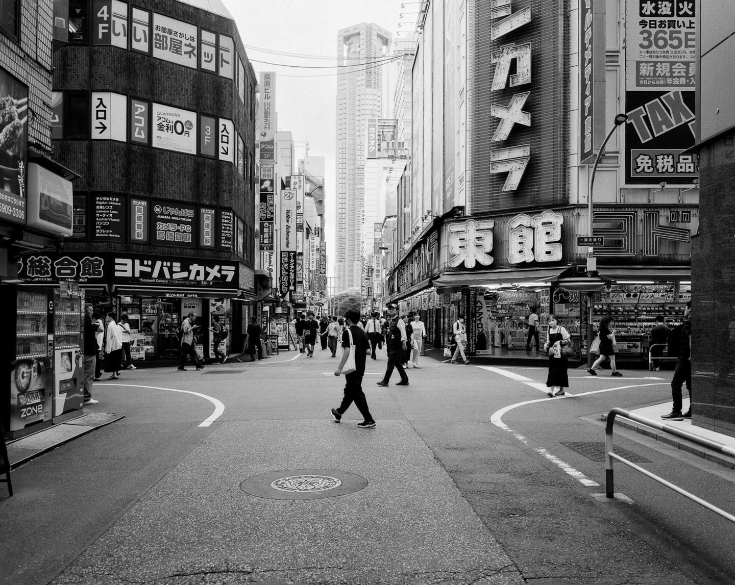 A street in a city is filled with pedestrians and tall buildings with many signs.