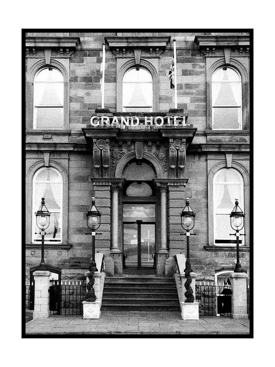 The facade of the Grand Hotel is visible with its entrance, windows, and two street lamps.