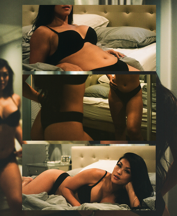 A woman in a black bra and underwear poses on a bed and in front of a mirror.