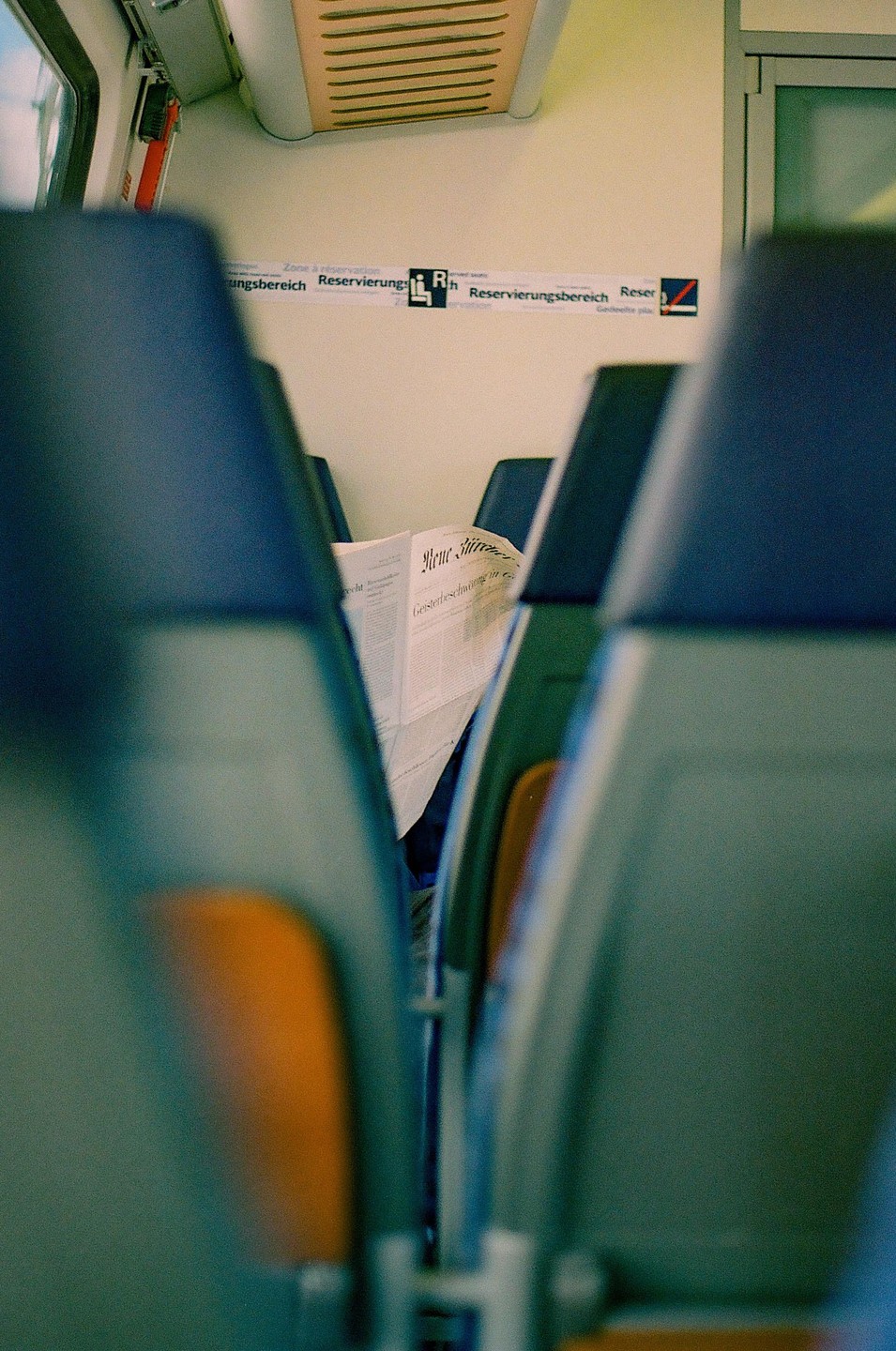 A newspaper is visible between two rows of seats on a train.