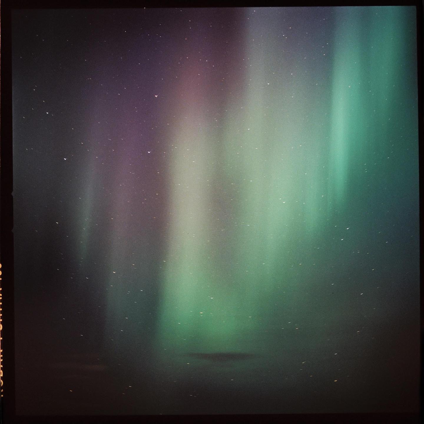 The aurora borealis illuminates the night sky with green and purple light.