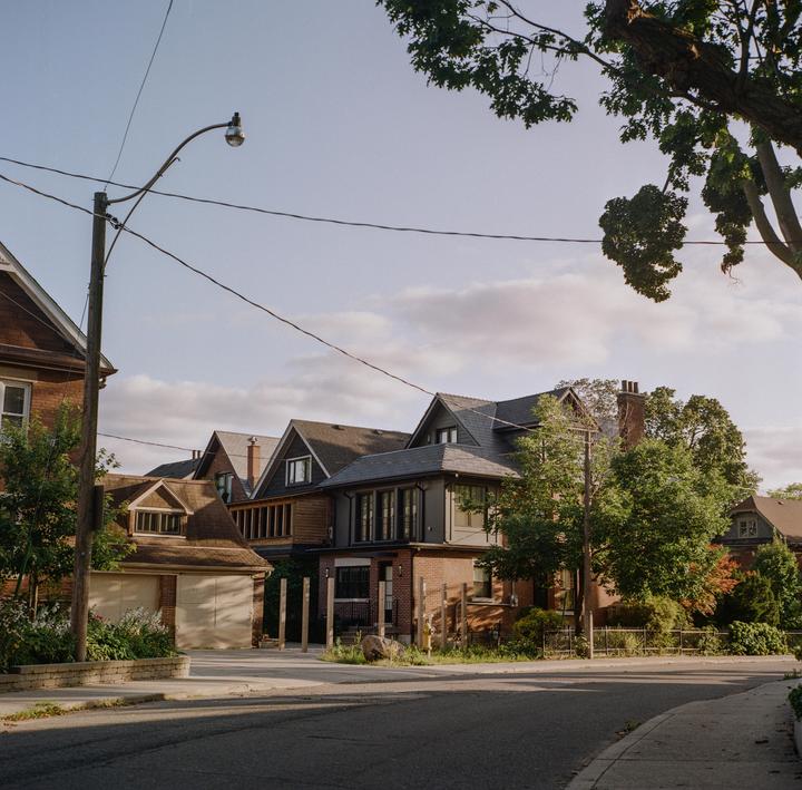 A street with houses and trees is visible under a partly cloudy sky.