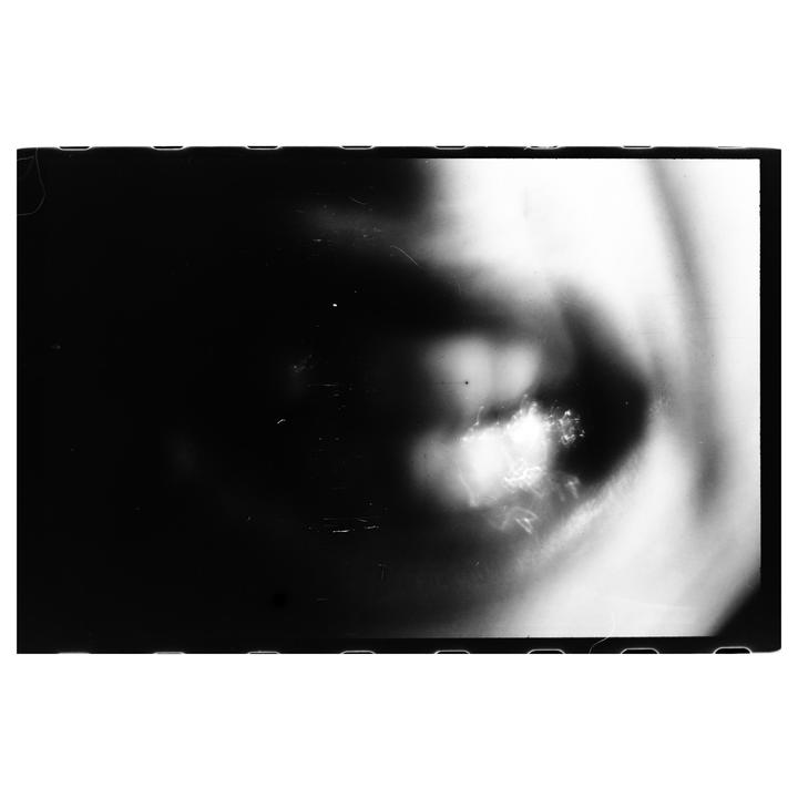 A black and white abstract image shows a bright, blurry shape on the right against a dark background.