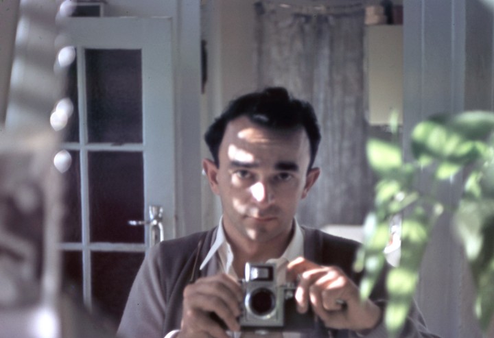 A man takes a self-portrait in a mirror while holding a camera.