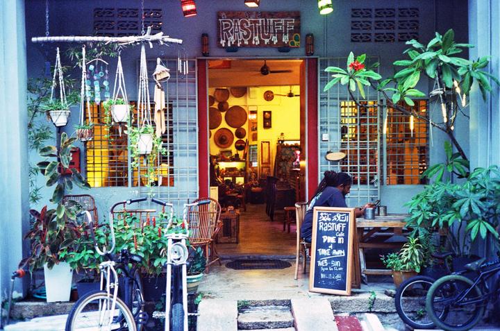A man sits at a table outside a cafe with a bicycle parked nearby.