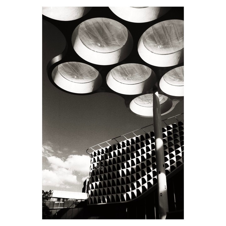 A building with a patterned facade is visible under a circular structure with lights.