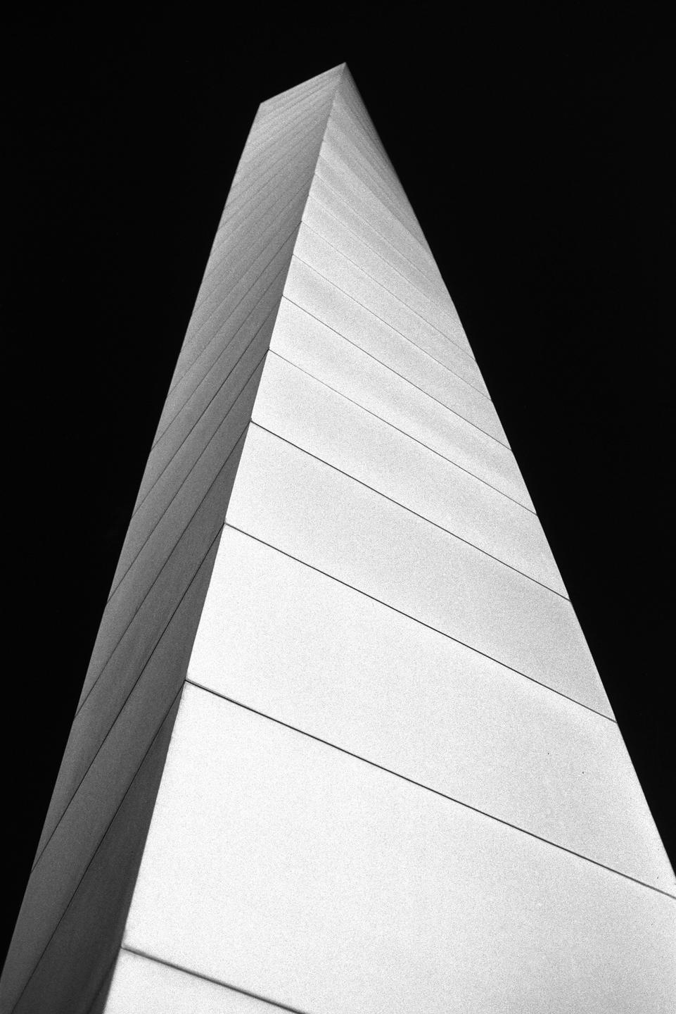 A tall, angular building with a pointed top stands against a dark sky.