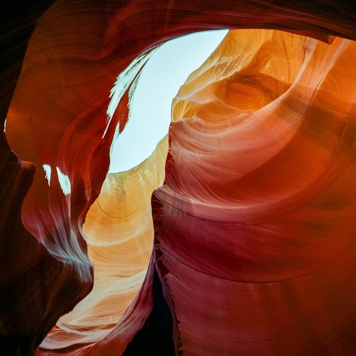 Light from above illuminates the red and orange sandstone walls of a slot canyon.
