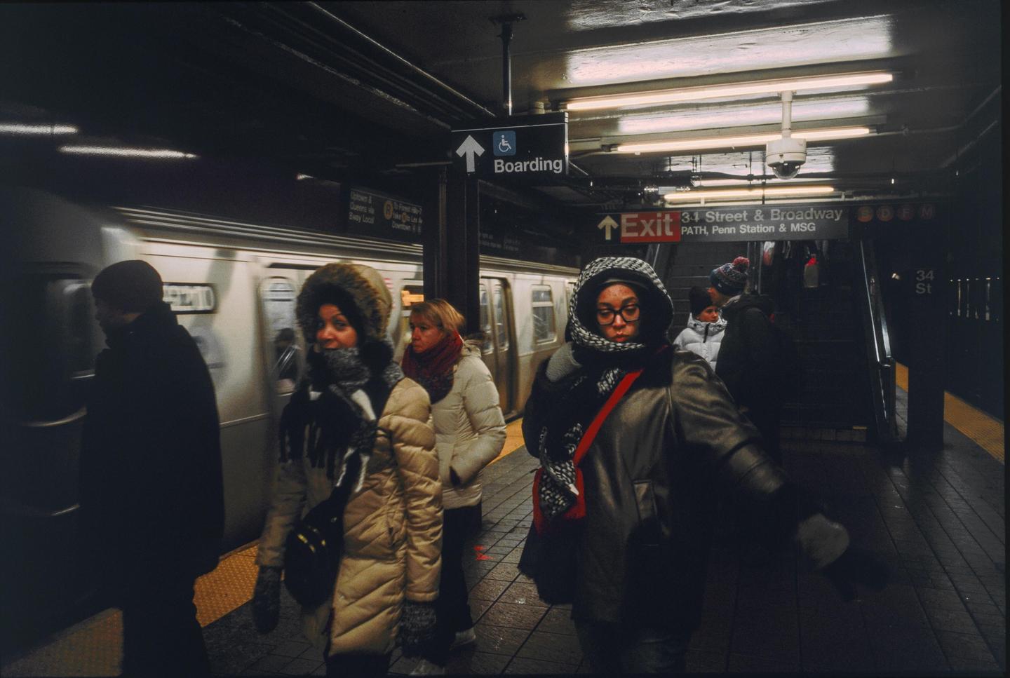 People wait on a subway platform as a train pulls into the station.