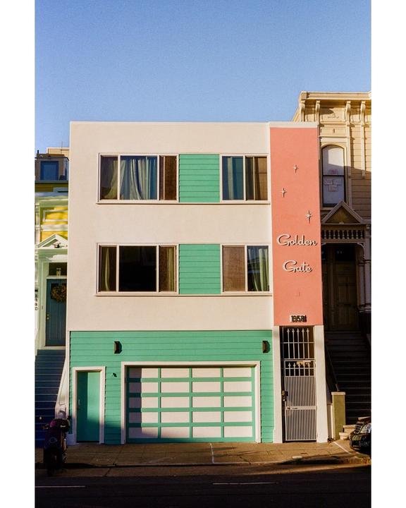 A colorful building with a garage and a sign that reads "Golden Gate" is shown on a sunny street.