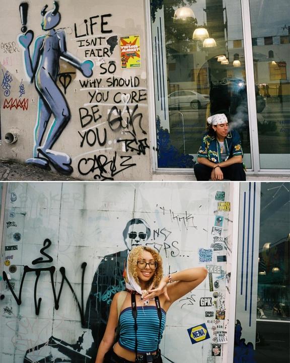 A man smokes a cigarette while sitting next to a wall with graffiti and a woman poses in front of a wall with graffiti.
