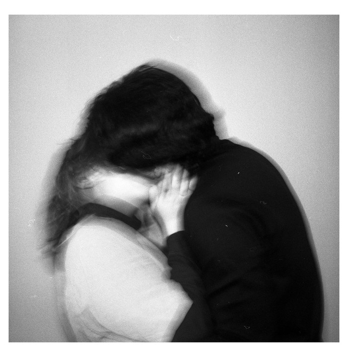 A blurry image shows a couple embracing, with one person's hand on the other's neck.