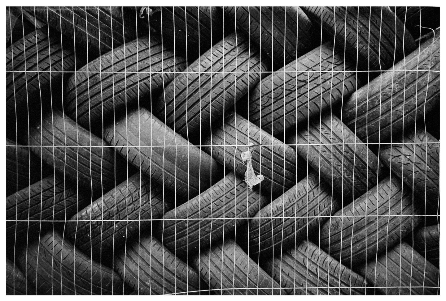 A stack of tires is visible through a wire fence.