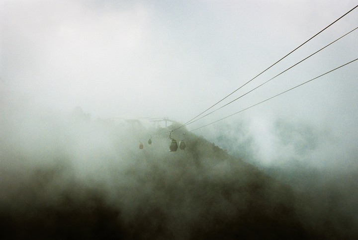 Several cable cars are visible on a foggy mountain with power lines stretching across the frame.