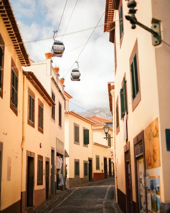 Two cable cars are visible above a narrow street lined with buildings.