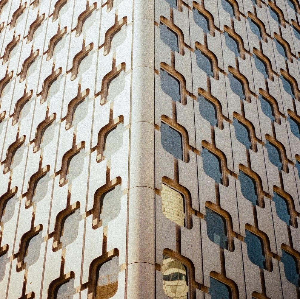 A building with a repeating pattern of windows and architectural details is shown from a low angle.