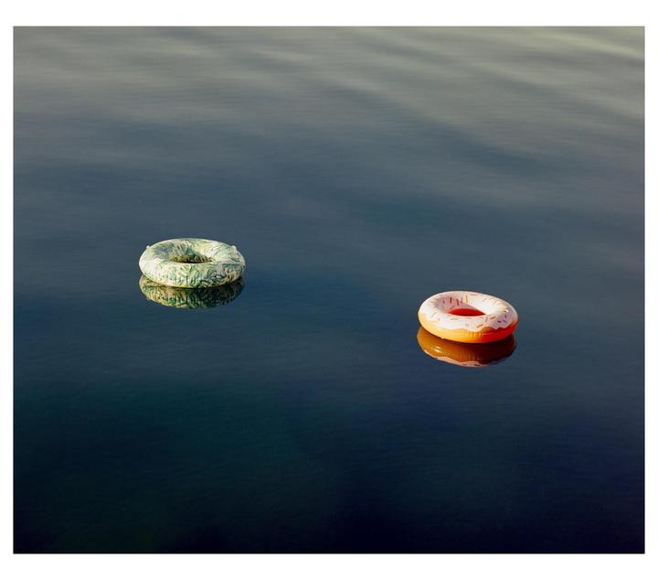 Two inflatable rings float on the surface of a calm lake.