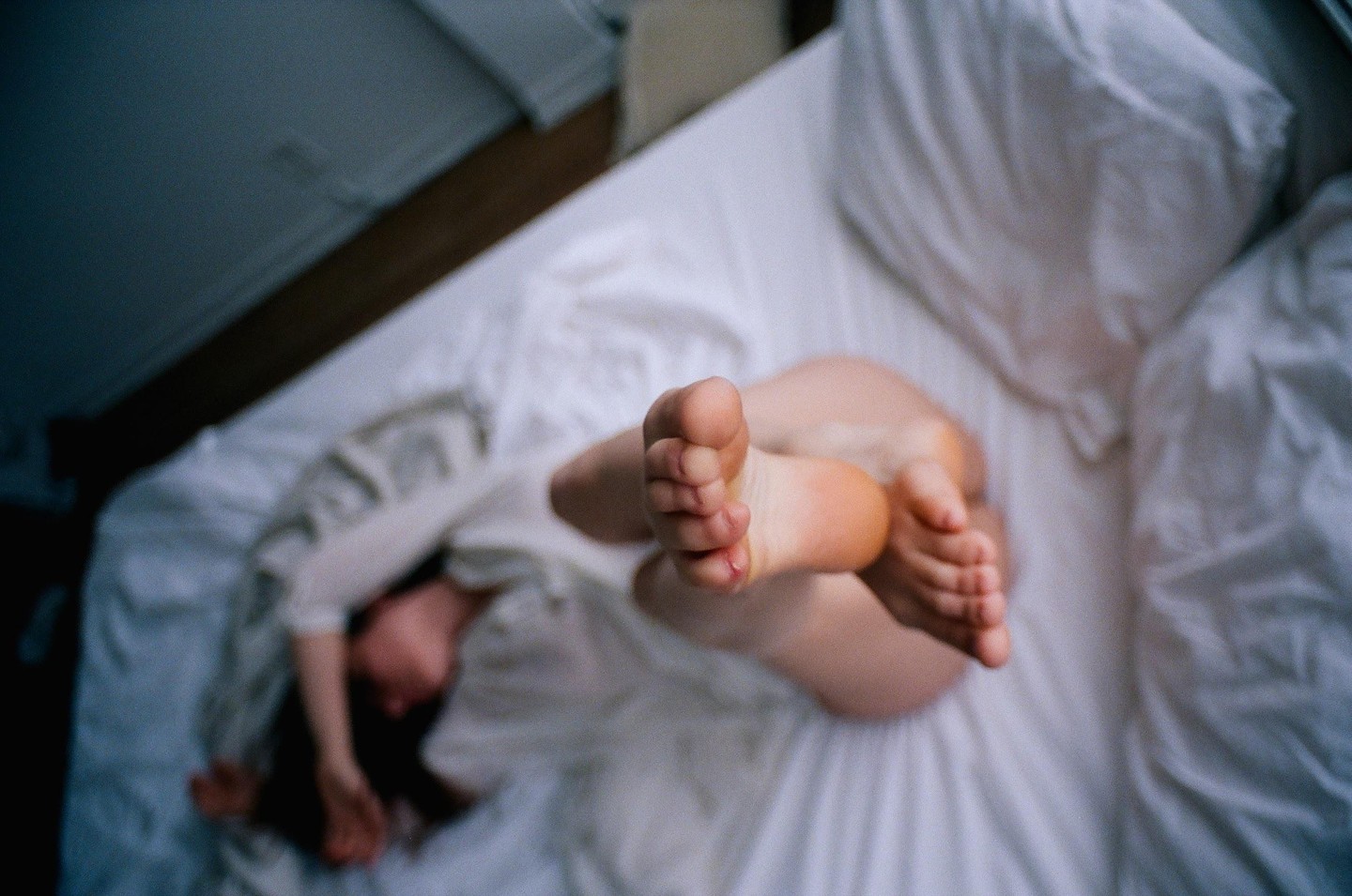 A woman lies on a bed with her feet in the air.