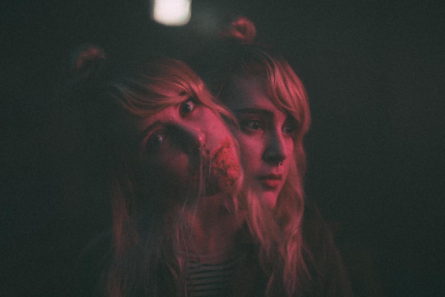 A woman's face is shown in a double exposure with red light.