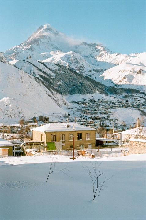 A snow-covered village with a large mountain in the background is visible under a clear sky.