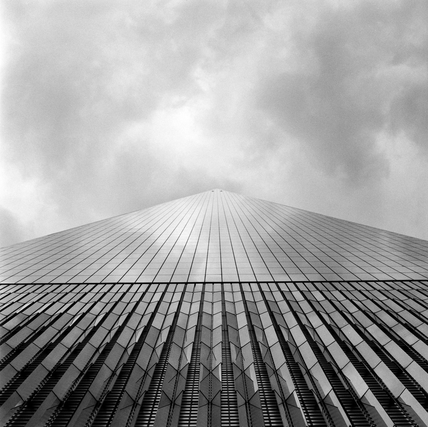 A low-angle view shows the facade of a skyscraper against a cloudy sky.