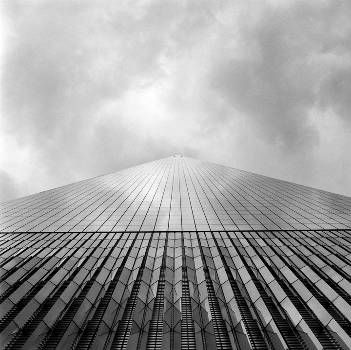 A low-angle view shows the facade of a skyscraper against a cloudy sky.