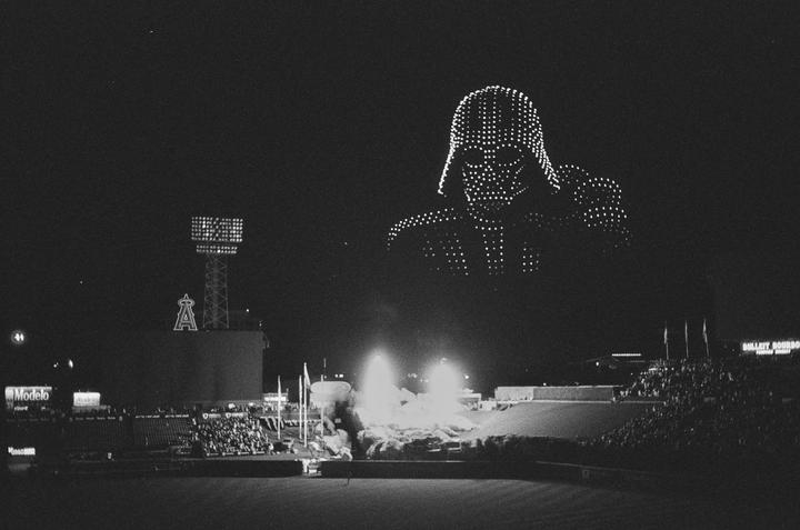 A drone show depicting Darth Vader is visible above a baseball stadium at night.