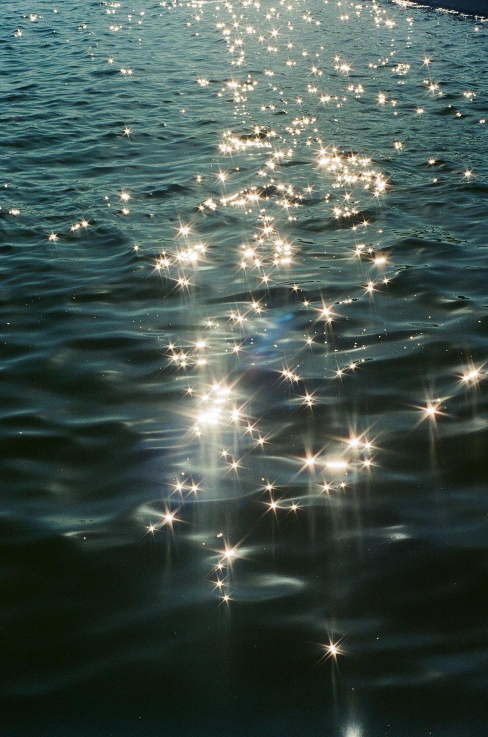 Sunlight sparkles on the surface of rippling water.