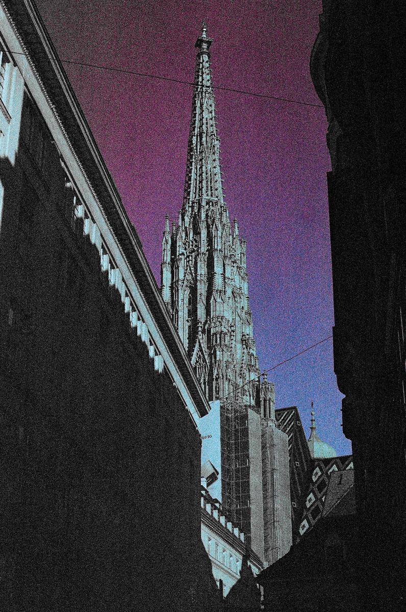 A tall, ornate spire rises above buildings against a purple and blue sky.