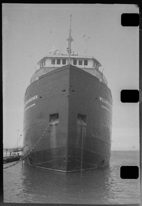 A large ship with a pointed bow is docked in the water, viewed from the front.