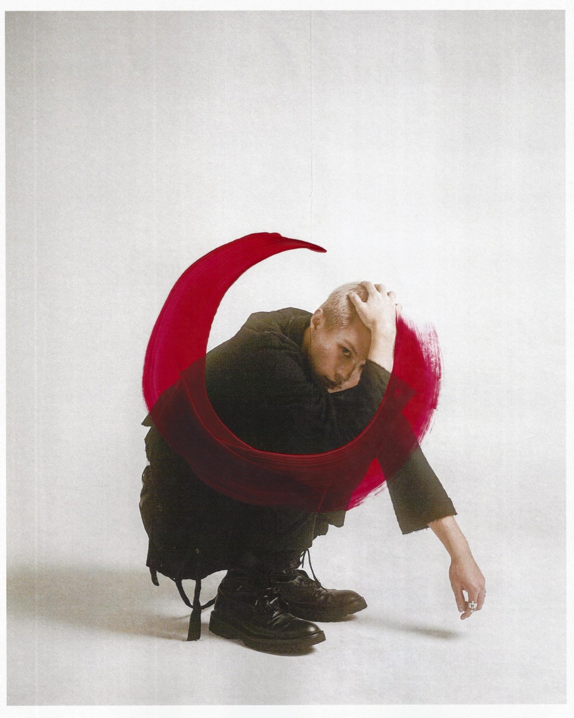 A man crouches with his head in his hands, surrounded by a red brushstroke.
